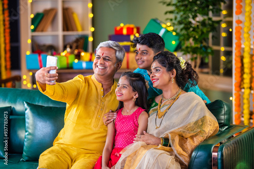 Canvas Print Indian family taking a festive Diwali selfie with while sitting on a sofa, captu