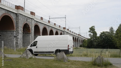 A leisurely train glides across the iconic Jezernicky viaduct in the Czech Republic. The tranquil beauty of the Czech countryside as the train slowly meanders through the lush landscape.