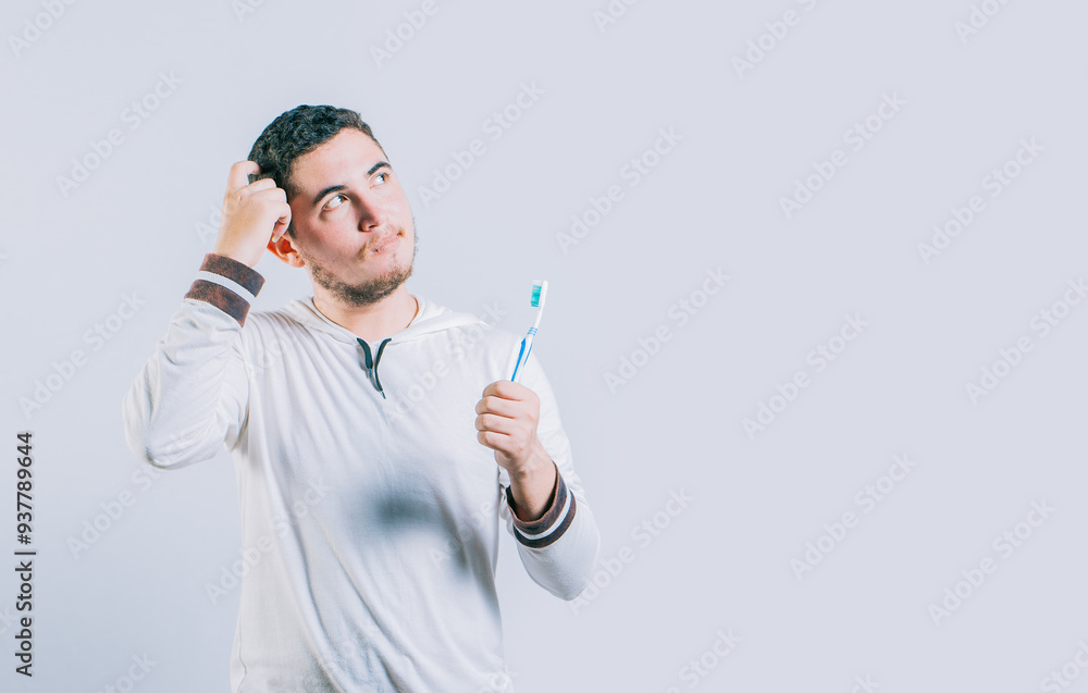 Thoughtful guy holding toothbrush looking up isolated. Worried young man holding toothbrush isolated. Thoughtful guy holding toothbrush looking up isolated. Worried young man holding toothbrush isolated.