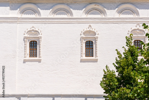 Windows with stucco and iron bars on the facade of an antique white brick building