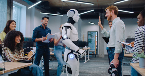 Multi-ethnic group of people gathering together to watch humanoid robot perform simple tasks. Asking questions and discussing results. Noting everything down on notepad. Man communicating with cyborg.