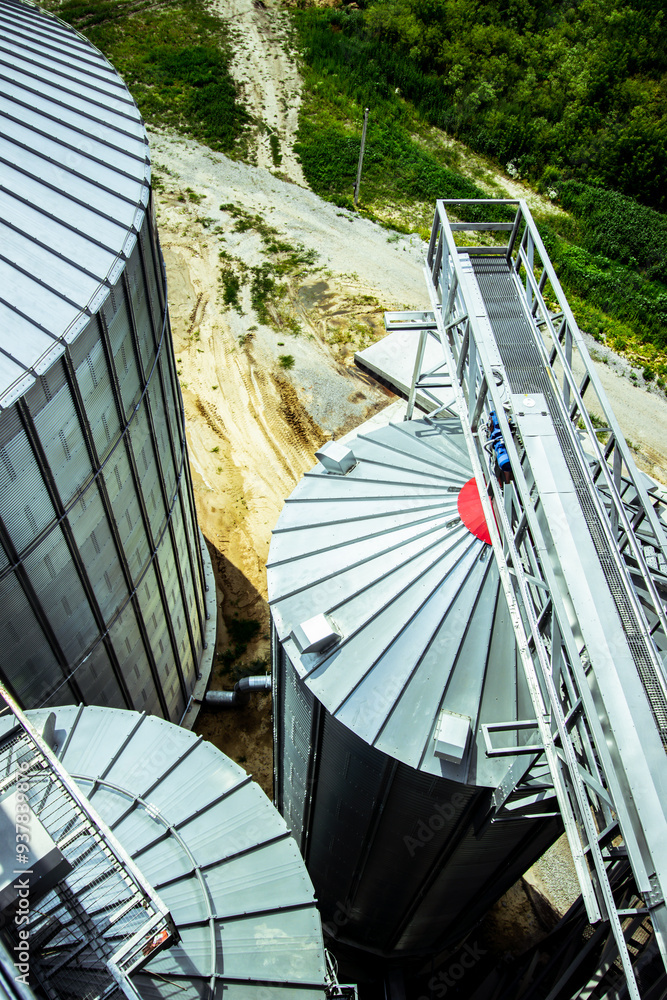 Close-up of large grain storage silos with precision-engineered metal roofs. Essential for high-capacity agricultural storage facilities. Vertical photo