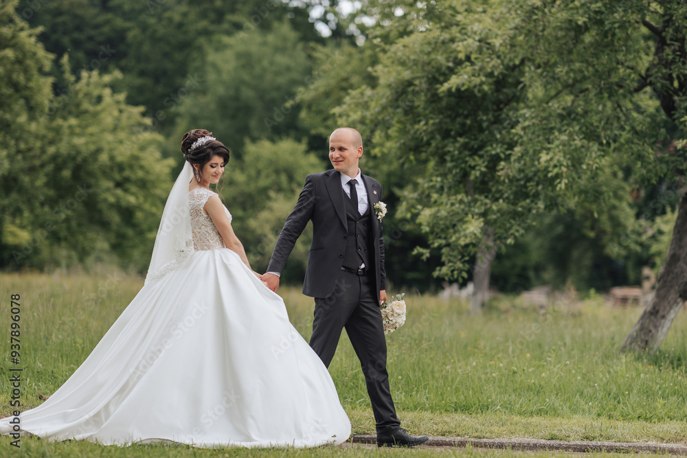 A bride and groom are walking together in a field. The bride is wearing a white dress and the groom is wearing a suit A bride and groom are walking together in a field. The bride is wearing a white dress and the groom is wearing a suit