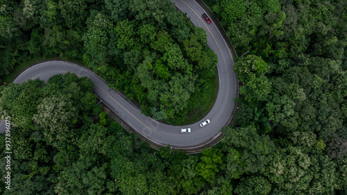 Aerial view car drive in green tree forest road winding road through the forest, Car drive on asphalt road between green tree forest, Electric vehicle EV car drive on asphalt road green tree forest.