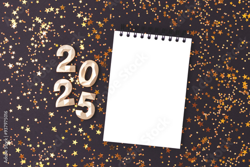 2025 New Year composition. Clean notepad mockup, glowing stars confetti and golden numbers on a black background.