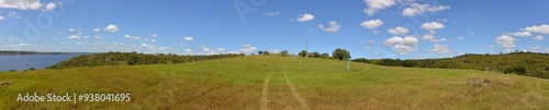 Panoramic photo of a lush green hay plantation under rural blue sky, grass texture and beautiful lake in the background. Beautiful morning light on green grass farm. Pedra do Cavalo Dam Lagoon photo