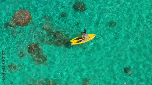 Woman gracefully gliding on a stand up paddle board in turquoise waters, exploring coral reefs from above. Perfect backdrop for a healthy, active summer vacation in the caribbean