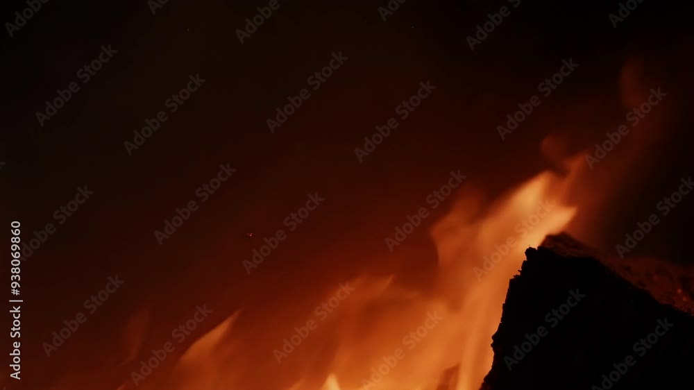 Flames are rising from burning firewood creating warm cozy atmosphere in fireplace at night. Close up view with blurred background Flames are rising from burning firewood creating warm cozy atmosphere in fireplace at night. Close up view with blurred background
