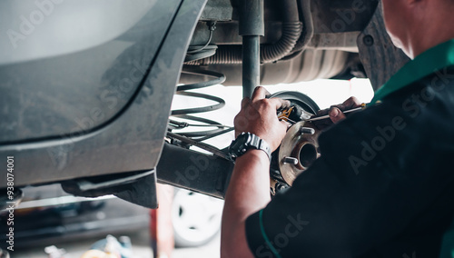 Canvastavla Close-up of a mechanic's hands repairing car brakes in a garage, focusing on vehicle maintenance and safety