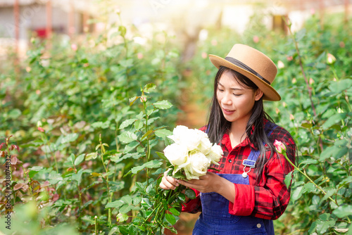 A smiling flower gardener holding a flower in hand in a garden.