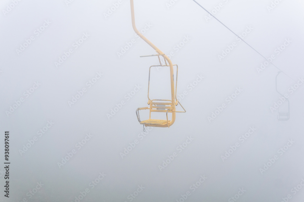 chair of chairlift over mountain slope in cloudy weather chair of chairlift over mountain slope in cloudy weather