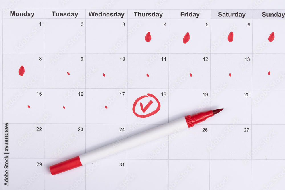 Hand draws red drops on the calendar, then places a red checkmark in a circle - concept of menstrual cycle tracking, ovulation, and pregnancy planning Hand draws red drops on the calendar, then places a red checkmark in a circle - concept of menstrual cycle tracking, ovulation, and pregnancy planning
