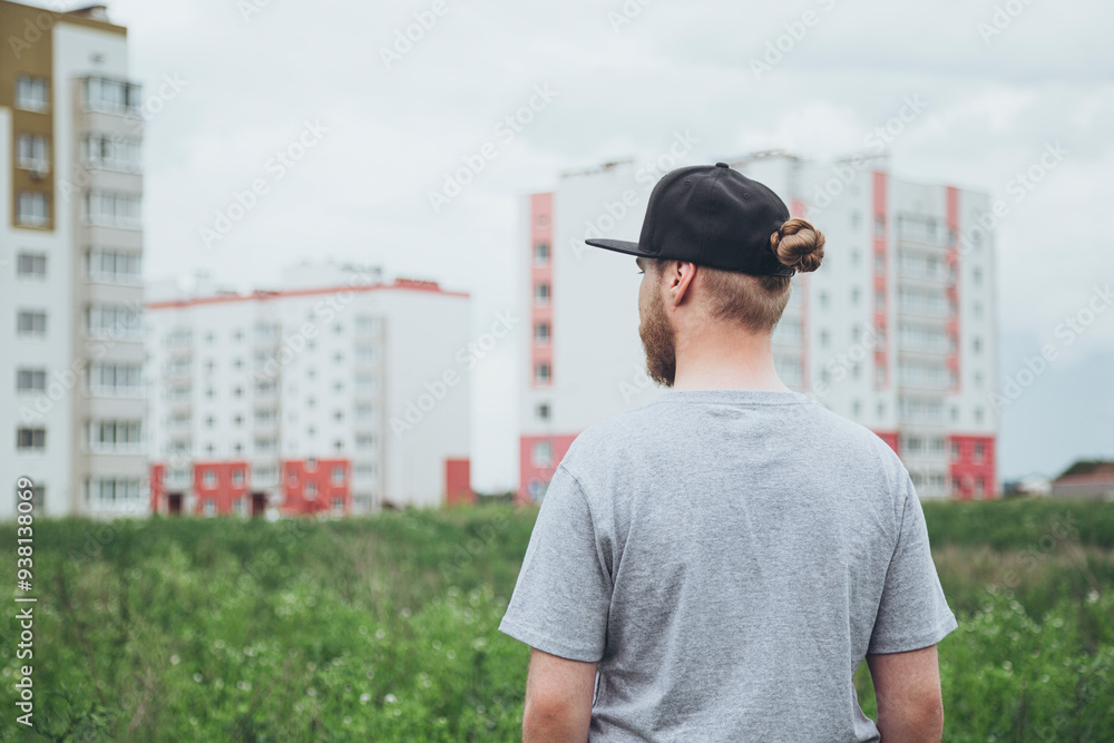 Fototapeta premium A man looks at the new buildings outside the city near the field.