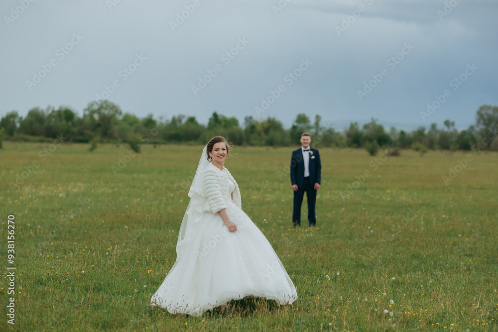 A bride and groom are standing in a field, with the bride wearing a white dress and the groom wearing a suit. Scene is romantic and happy, as the couple is getting married A bride and groom are standing in a field, with the bride wearing a white dress and the groom wearing a suit. Scene is romantic and happy, as the couple is getting married