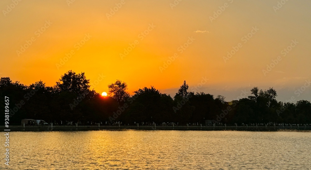Beautiful sunset with golden sky in front of a lake in Madrid, Spain