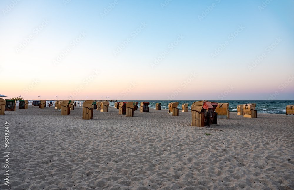 Obraz premium Dahme, Germany - Sunset over the beach with beach baskets or Strandkörbe