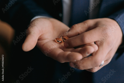 A man is holding two gold wedding rings in his hand