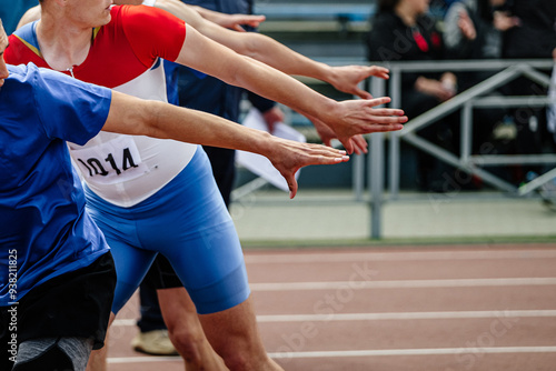 four hands of athletes waiting to pass baton in athletics competition