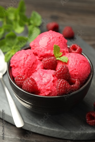 Delicious raspberry sorbet with fresh berries in bowl and spoon on table, closeup