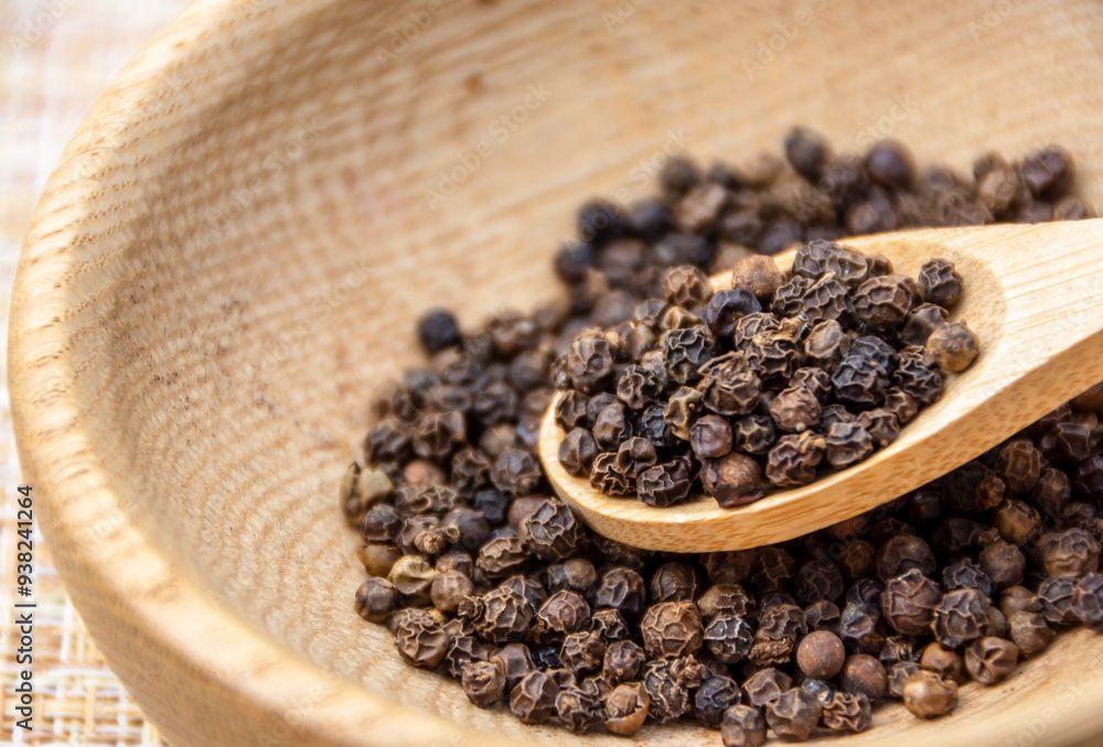 Dry black pepper spice on a wooden spoon close up. Black peppercorns. Dry black pepper spice on a wooden spoon close up. Black peppercorns.