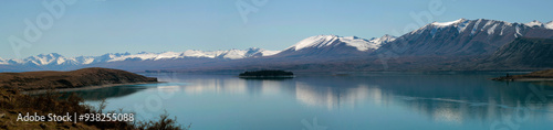 panoramic view of the lake with island and mountains with snow in summer