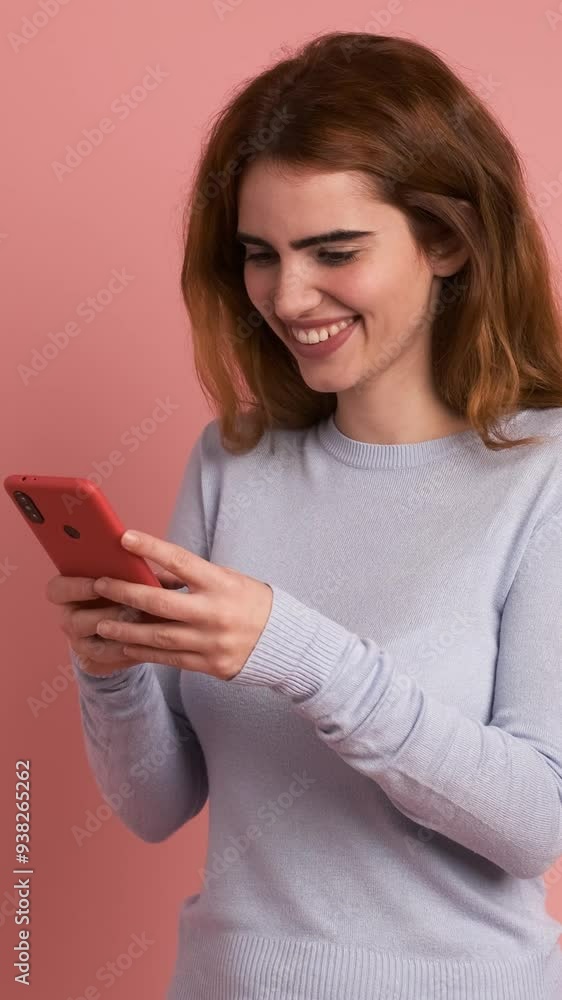 Smiling woman using mobile phone in pink studio. Vertical Footage Smiling woman using mobile phone in pink studio. Vertical Footage