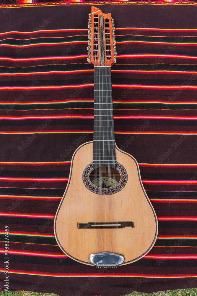 Fototapeta premium Traditional Andean instruments elegantly arranged on a striped textile. The Charango, Mandolin, and Bandolina are artfully crossed, highlighting their fine details and cultural significance.