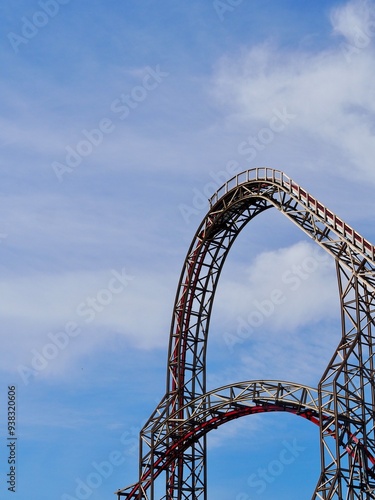 A close-up image of a red rollercoaster track and the blue sky in the background in the amusement park. photo