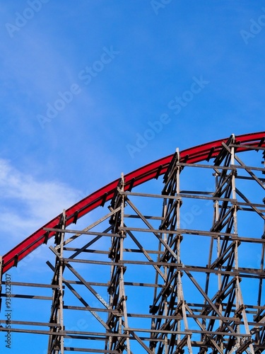 A close-up image of a red rollercoaster track and the blue sky in the background in the amusement park. photo