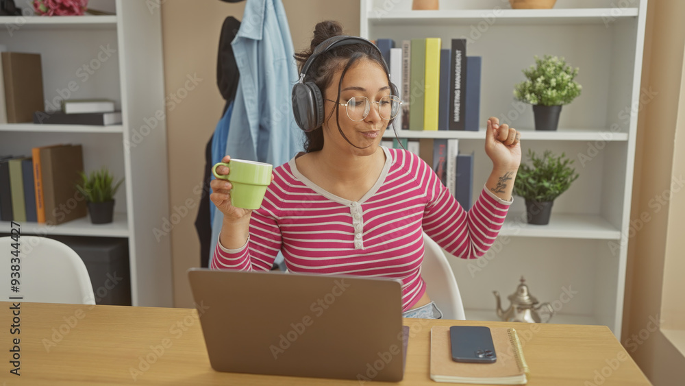 Young hispanic woman enjoying music with headphones at home, sip coffee, dance casually, cozy interior. Young hispanic woman enjoying music with headphones at home, sip coffee, dance casually, cozy interior.