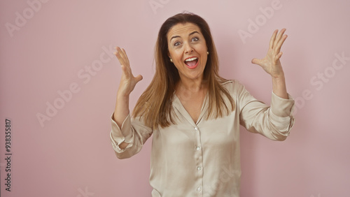 Excited woman with open arms and a surprised expression on a pink background