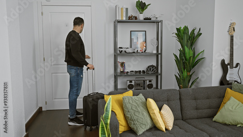Bild auf Leinwand A young hispanic man with luggage in a modern living room ready to depart
