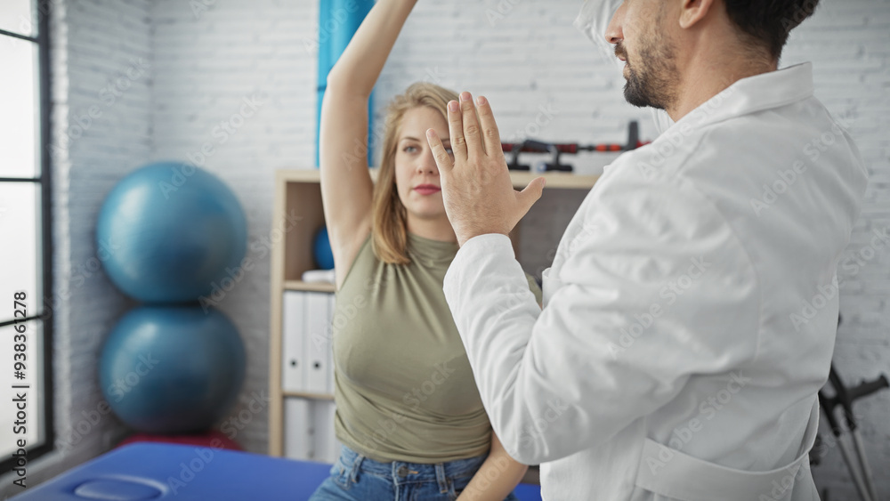 Obraz premium A woman patient exercises under the guidance of a male physiotherapist in a clinic room.
