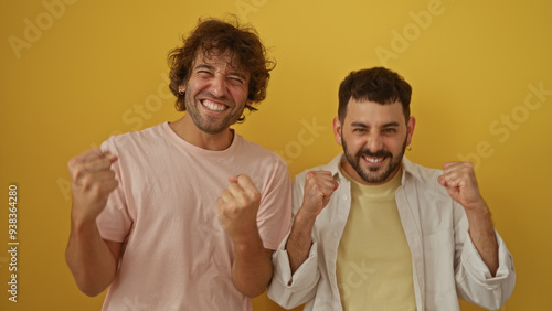 Men friends celebrating and smiling together against an isolated yellow background, showing a strong brotherly bond and family connection in a vibrant scene.