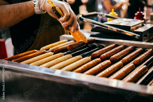 Obraz na płótnie A vendor fries sausages at a hot dog stand. w salonie