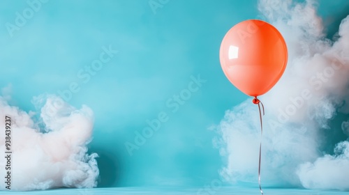 A single orange balloon hovers against a teal-colored background filled with white fog, creating a surreal and serene atmosphere that evokes a sense of dreaminess and calm.