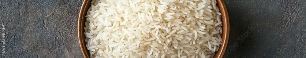 Bowl of uncooked white rice on a textured surface Bowl of uncooked white rice on a textured surface
