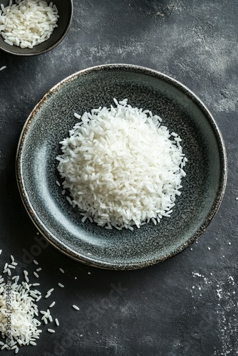 Freshly cooked white rice served in a dark bowl on a textured surface