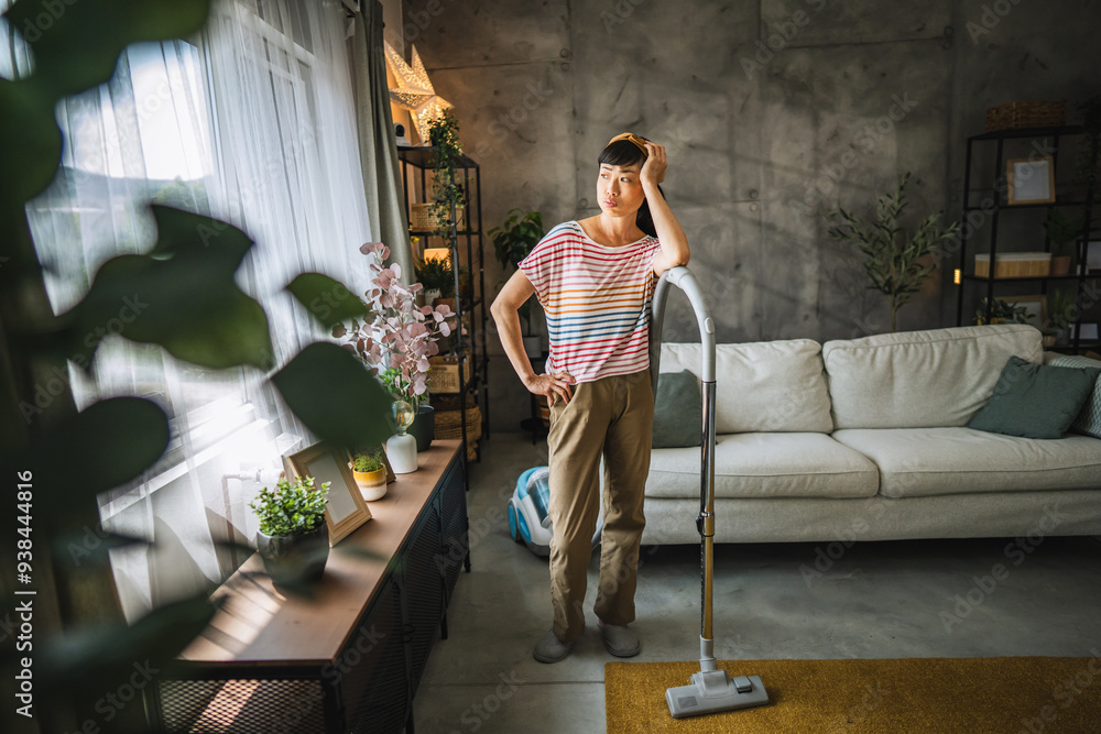 Fototapeta premium Exhausted, tired mature japanese woman stand with a vacuum cleaner