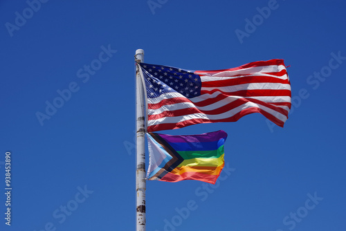 United States of America above a Rainbow Flag waving under blue sky