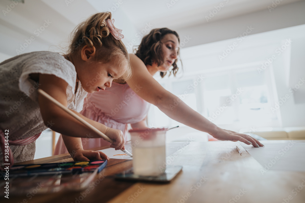 Mother and young daughter painting together at home, enjoying creative and quality bonding time in a bright room. Mother and young daughter painting together at home, enjoying creative and quality bonding time in a bright room.