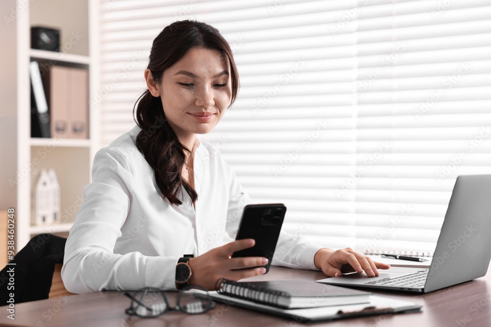 Beautiful young businesswoman using smartphone in office Beautiful young businesswoman using smartphone in office
