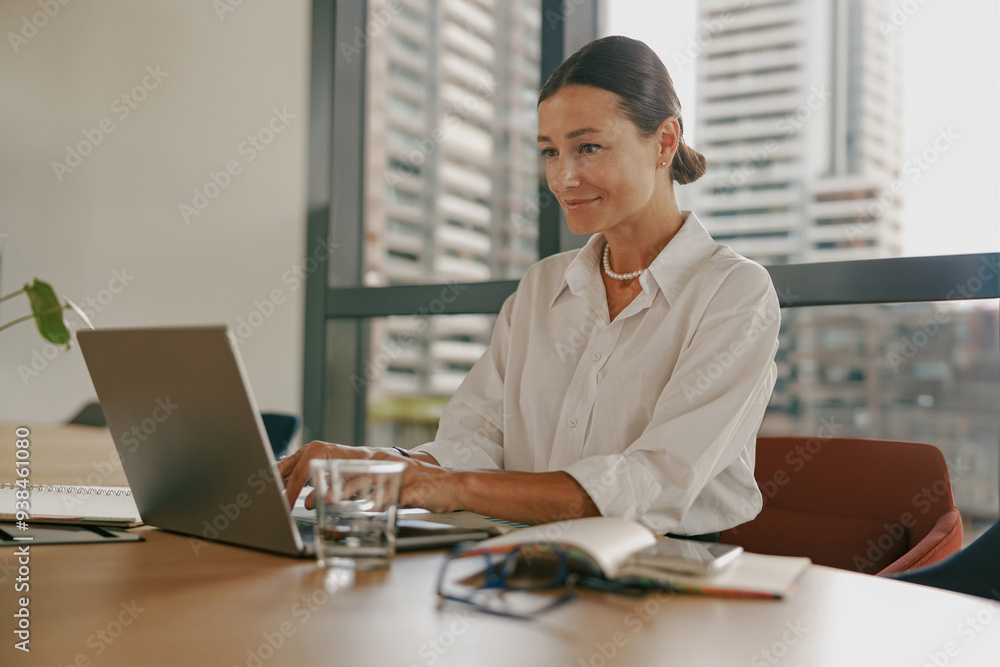A woman is working diligently on her laptop in a contemporary and modern office space A woman is working diligently on her laptop in a contemporary and modern office space