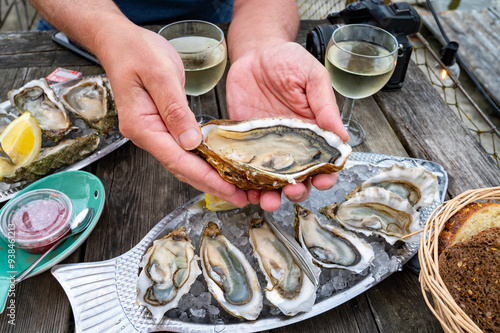 Cuadro en lienzo Eating of fresh live oysters with citron at farm cafe in oyster-farming village,