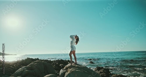 Woman standing on rocks modeling while waves crash in the background