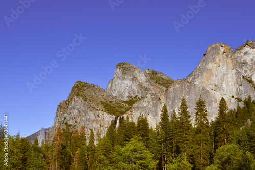 Yosemite waterfall mountain. Sunny day, light blue sky. Forest and trees. Desktop mobile wallpaper.