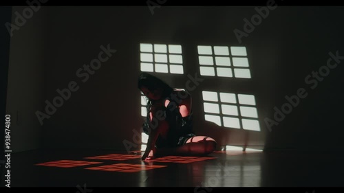 Woman sitting on wood floor swaying back and forth with shadow from window light