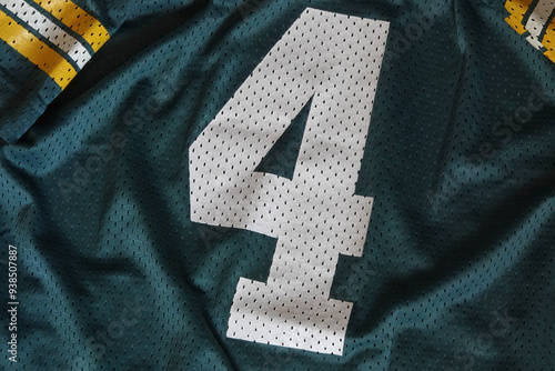 Number 4 is displayed up close on a green, white, and yellow mesh sports jersey.