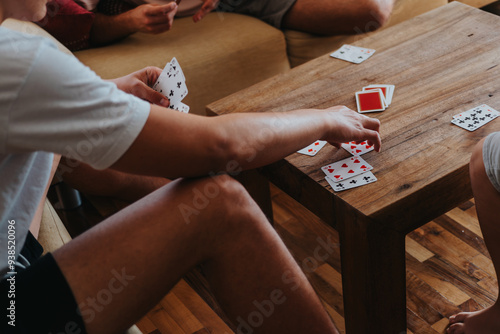 Boys playing cards game around a wooden table at home. A fun and engaging activity with friends.