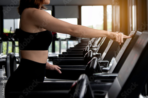 Obraz na płótnie photo portrait of a young woman exercise in gym, running use thereadmill machine equipment, healthy lifestyle, cardio exercise in fitness club concepts. w salonie